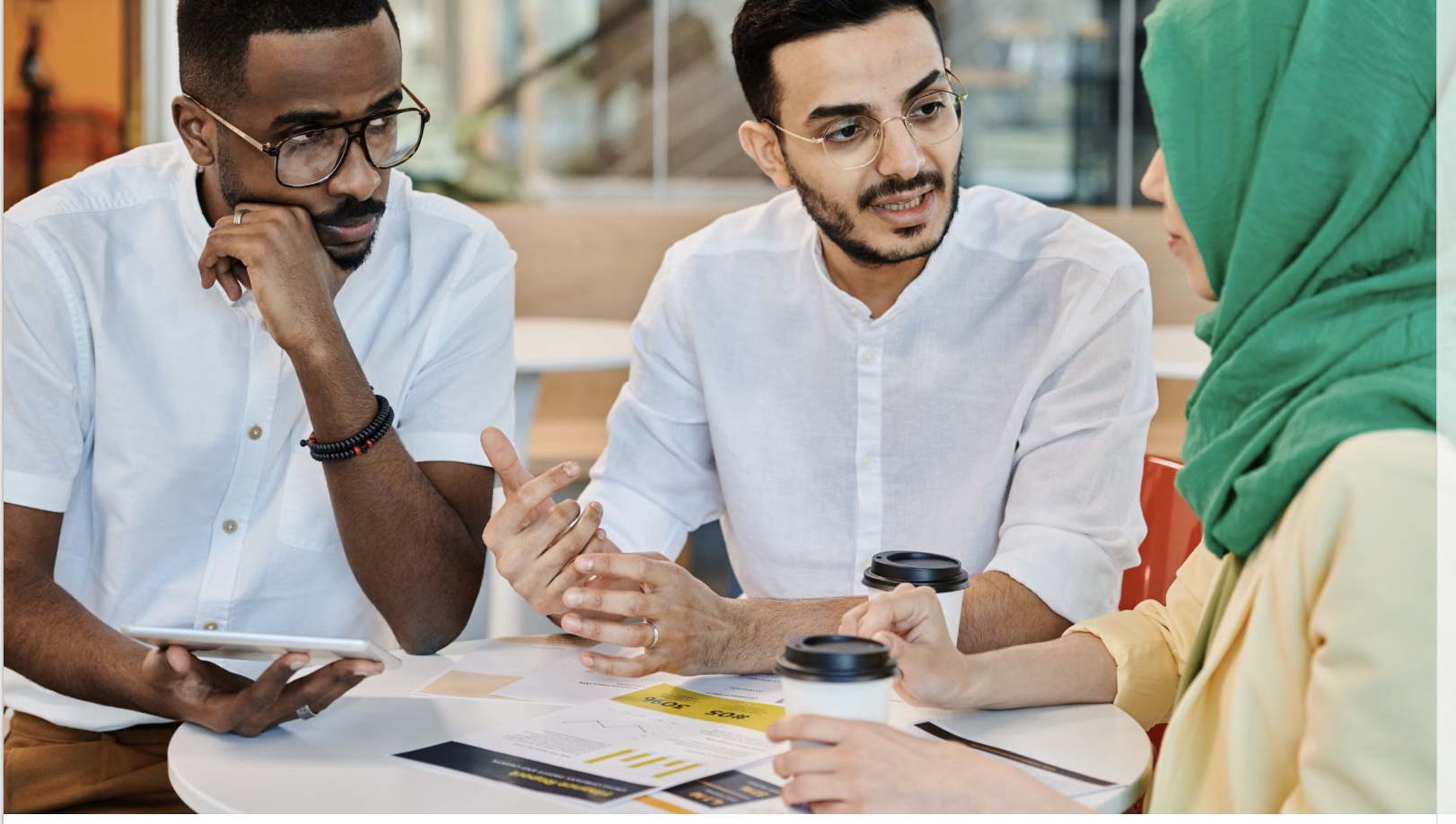 Three business professionals discussing plans together around a table