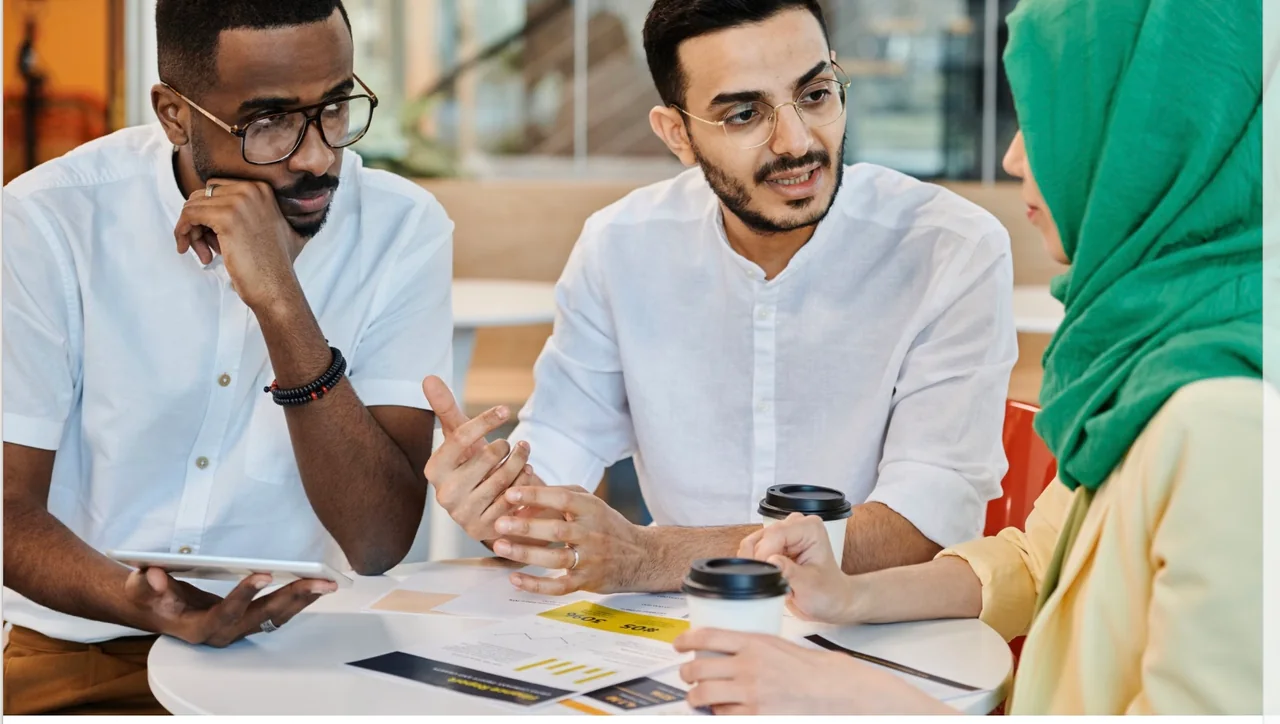 Three business professionals discussing plans together around a table
